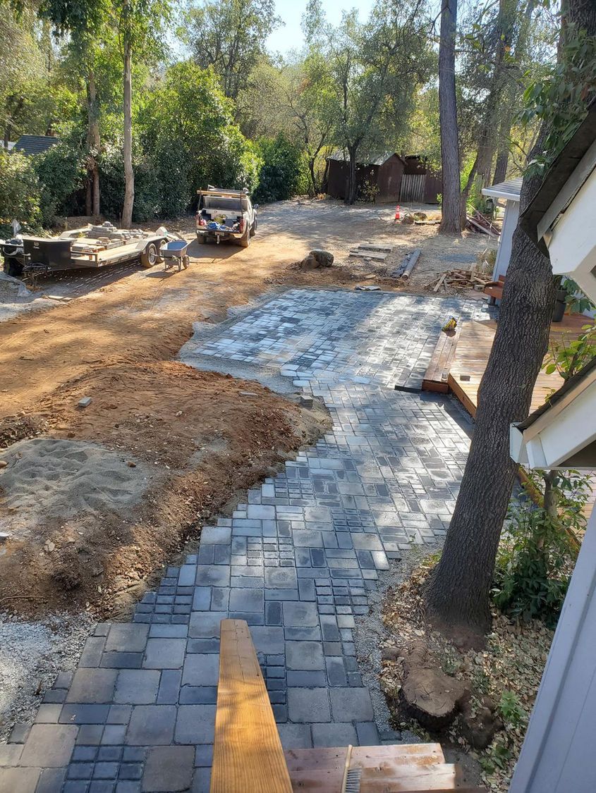 A brick walkway is being built in the backyard of a house.