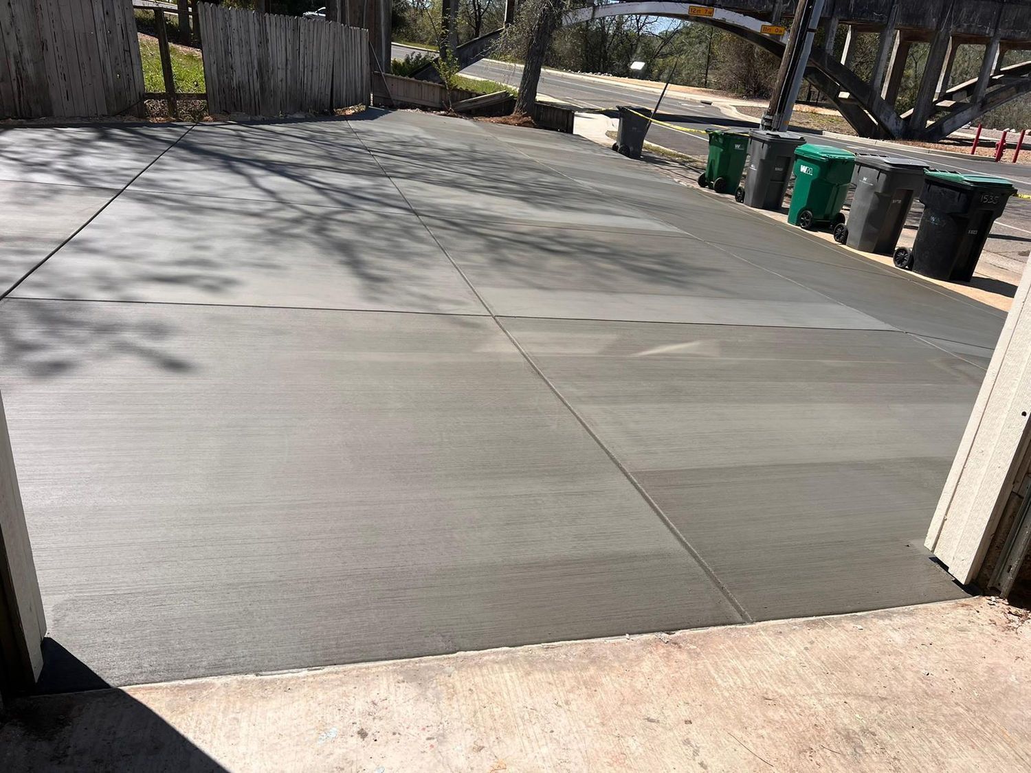 A concrete driveway with a lot of trash cans in it.