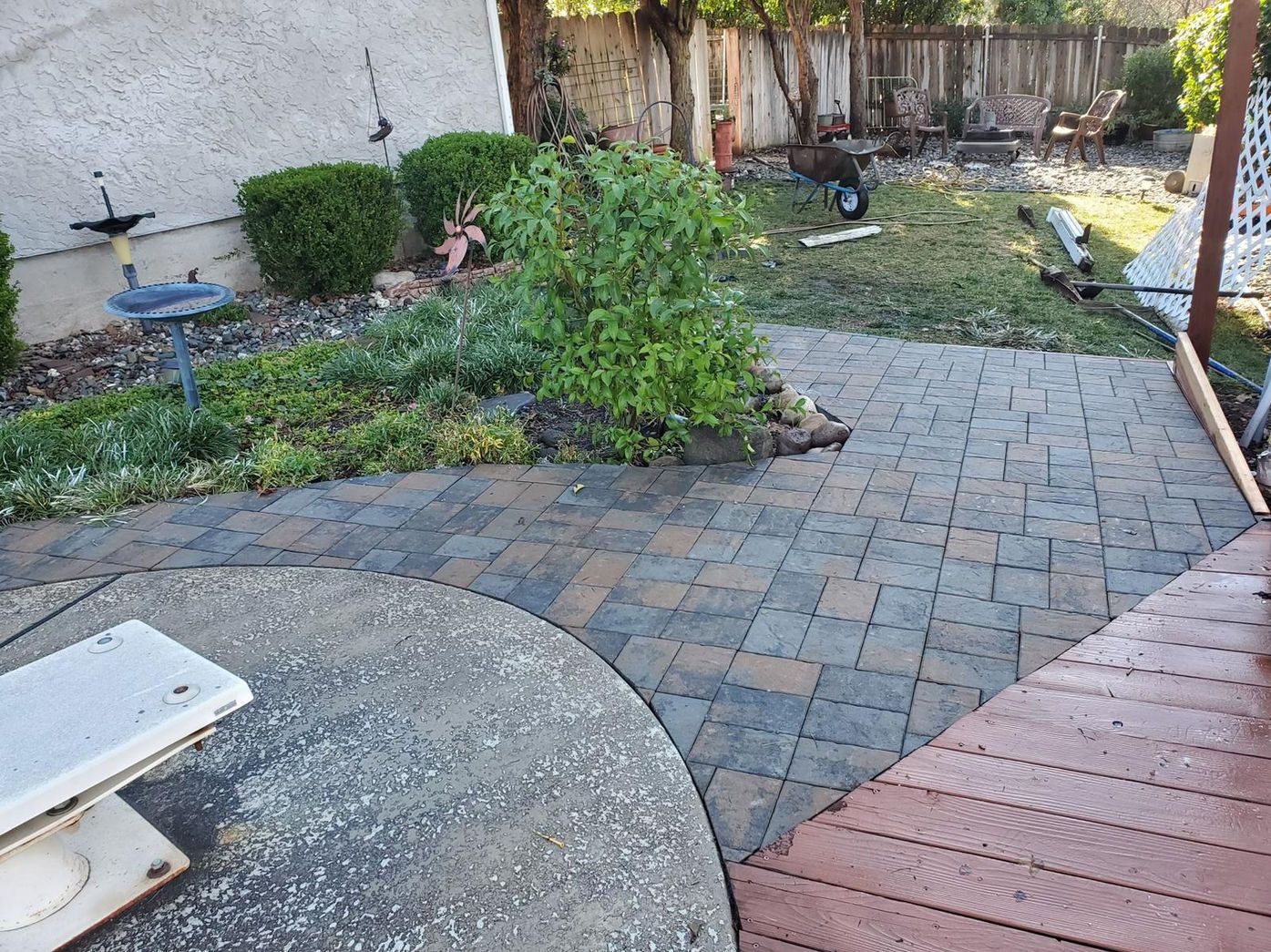 A backyard with a brick walkway and a wooden deck.