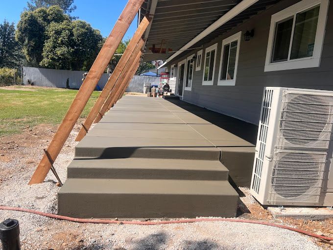 A concrete walkway is being built in front of a house.