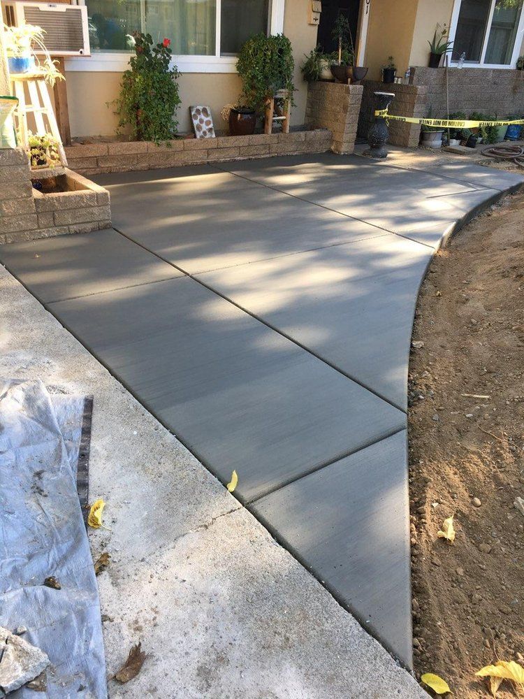 A concrete driveway is being built in front of a house.