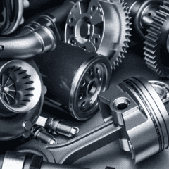 Detalhe de diversas peças do motor: engrenagens, filtro, turbocompressor, pistão, velas de ignição e tubos em tons metálicos.