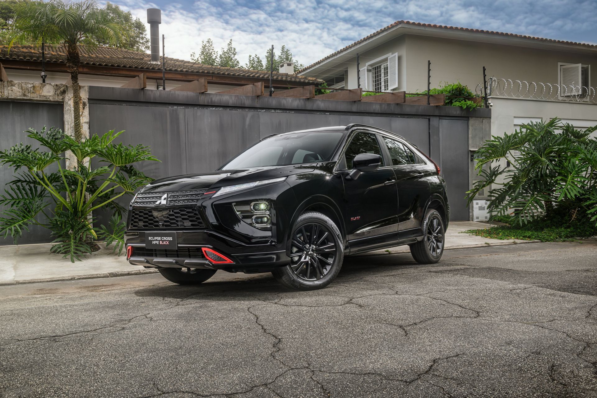 SUV preto estacionado em uma entrada pavimentada em frente a uma casa.