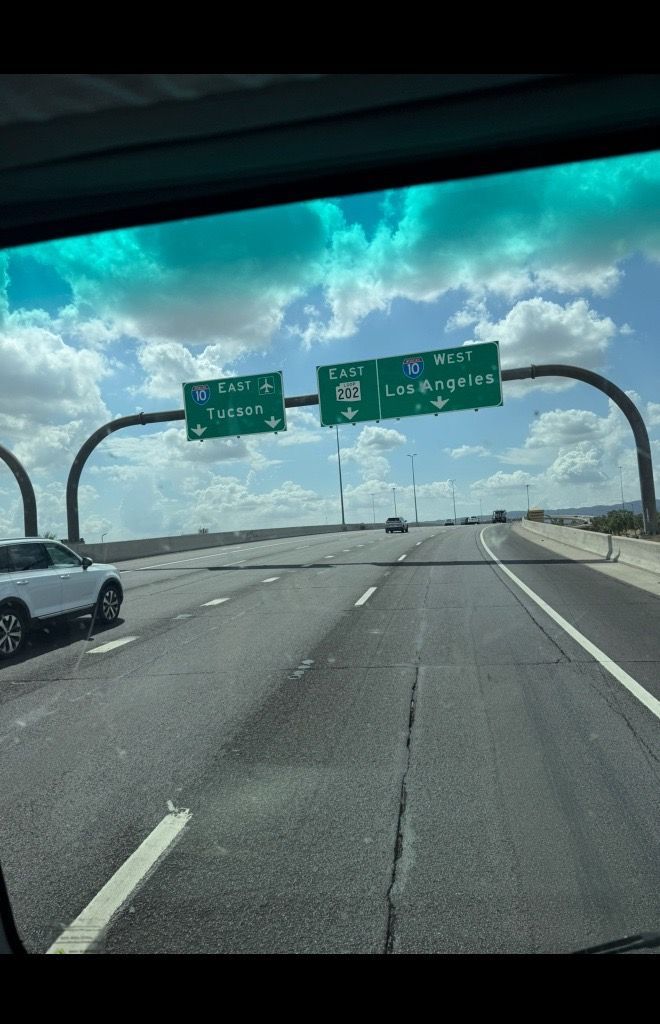 Highway road sign for exits to Tucson and Las Vegas, seen from a moving vehicle.