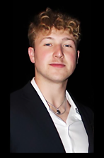 A young man in a suit and white shirt is standing in front of a black background.