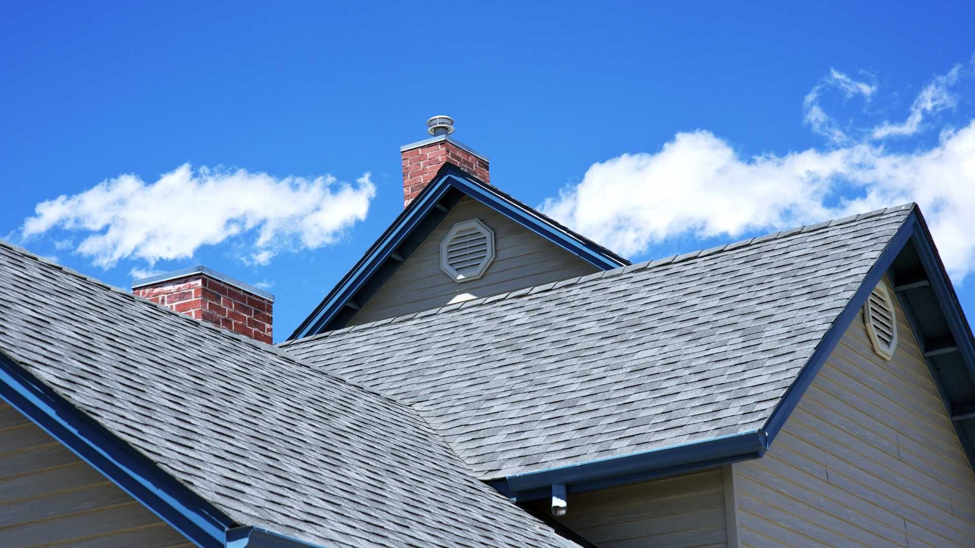 A house with a gray roof and a chimney on top of it.
