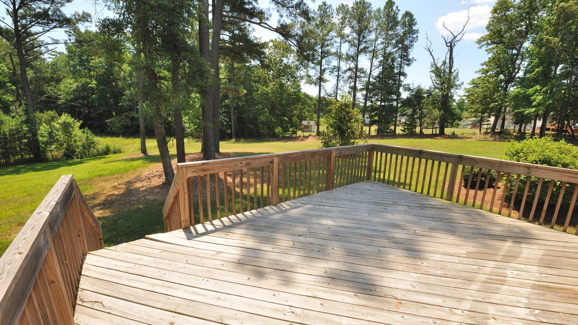 A wooden deck with a fence and trees in the background