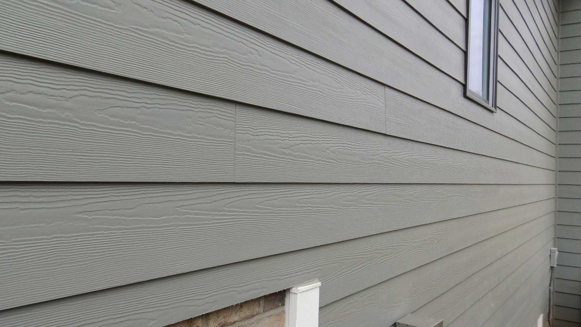 The side of a house with a gray siding and a window.