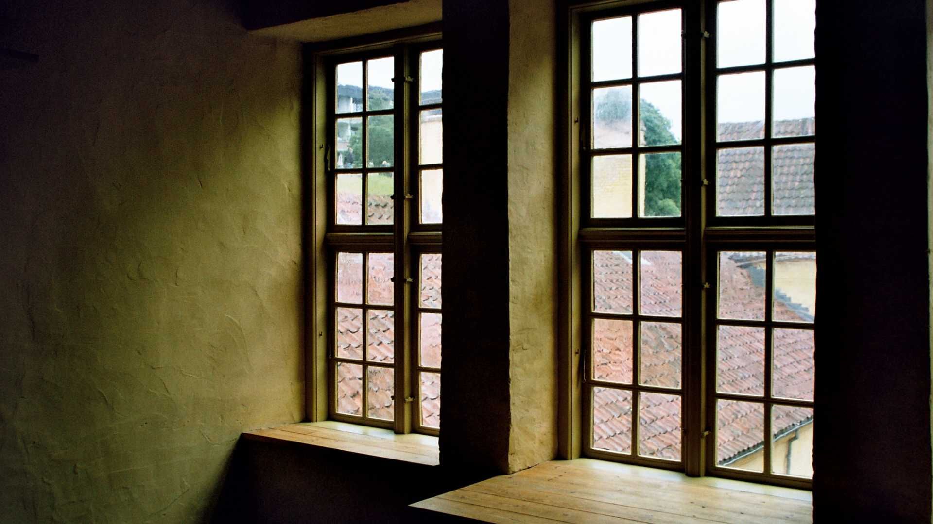 A room with two windows and a wooden table
