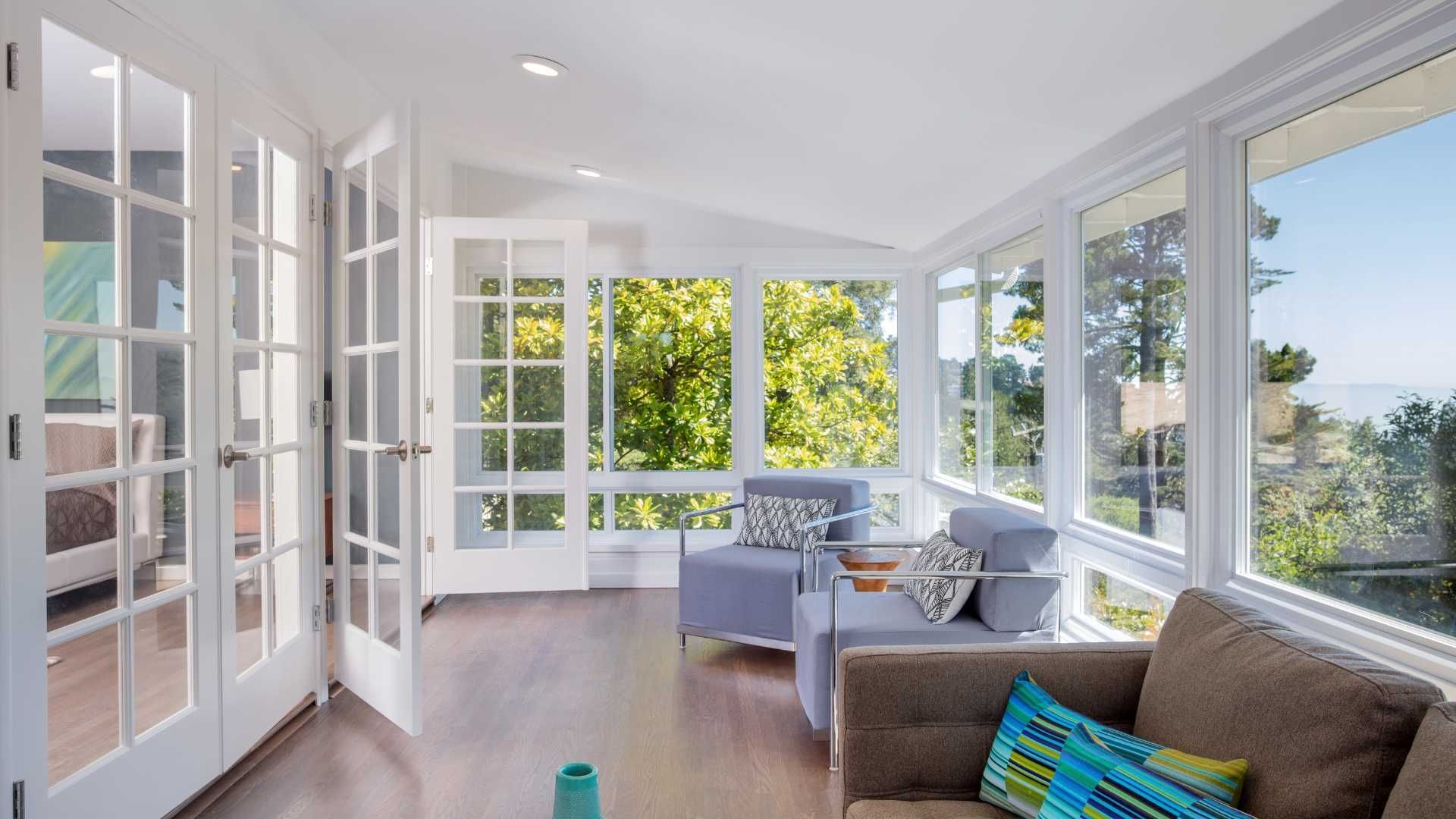 A living room with a couch , chairs , and a lot of windows.