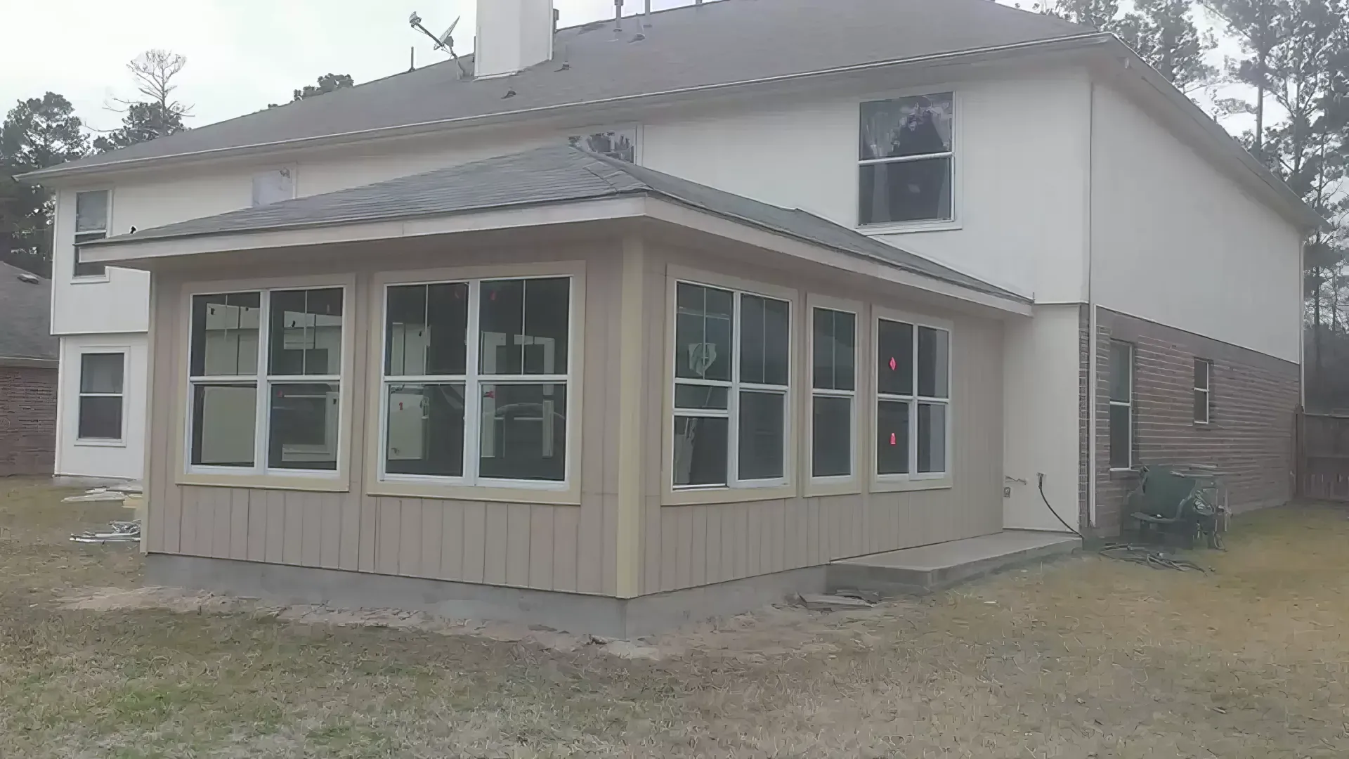 The back of a house with a screened in porch and a lot of windows.