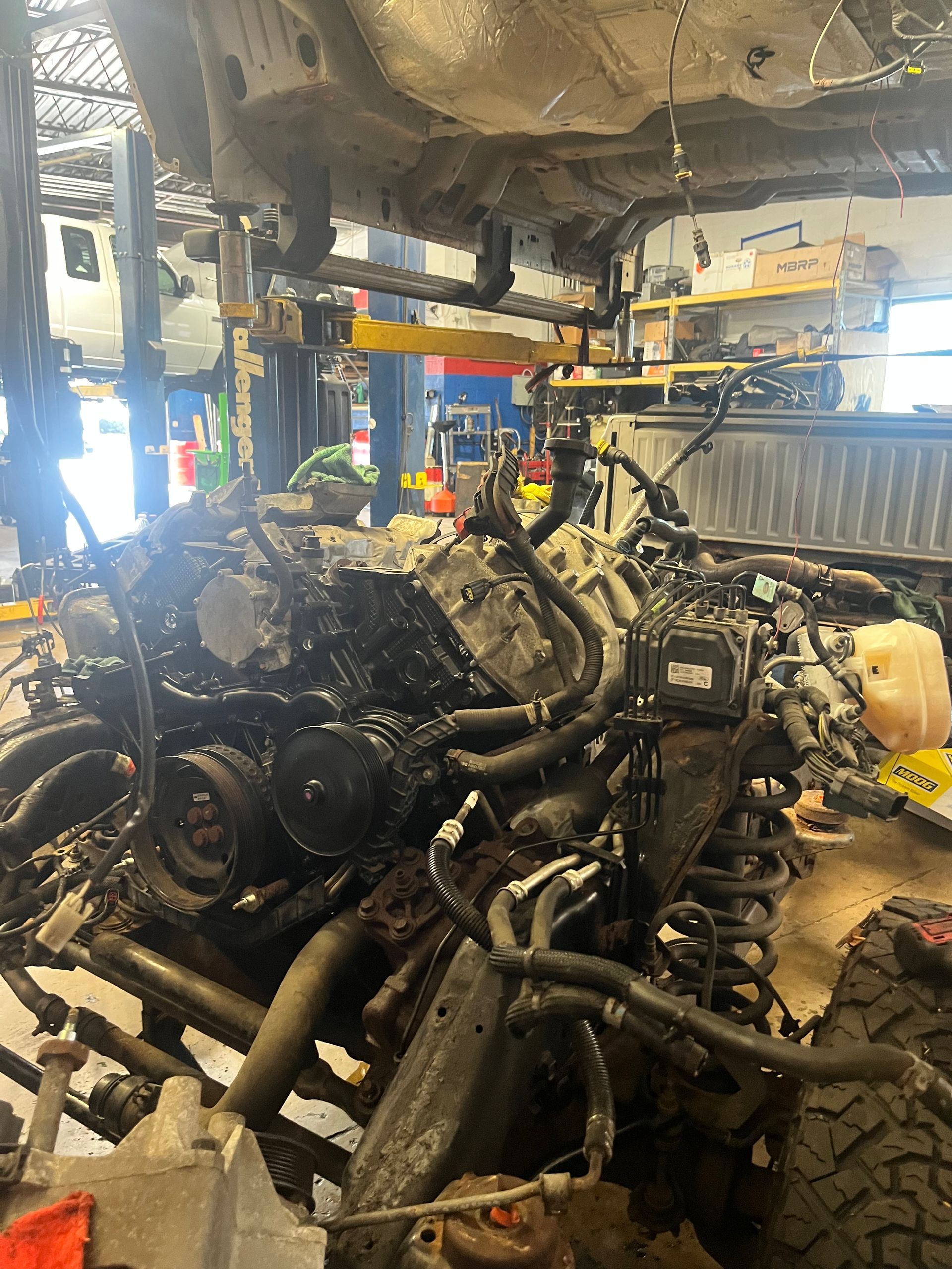 A car engine is being removed from a truck in a garage.