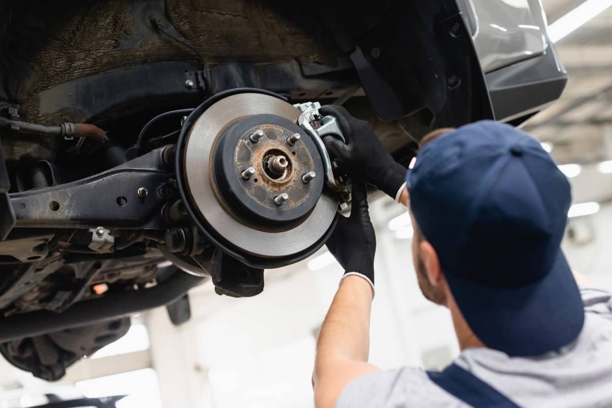 A man is working on the brake disc of a car.