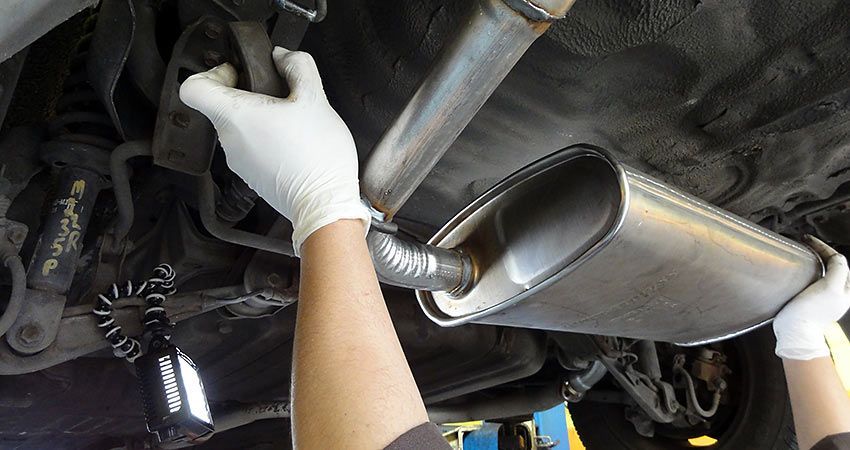 A person is working on the exhaust pipe of a car.
