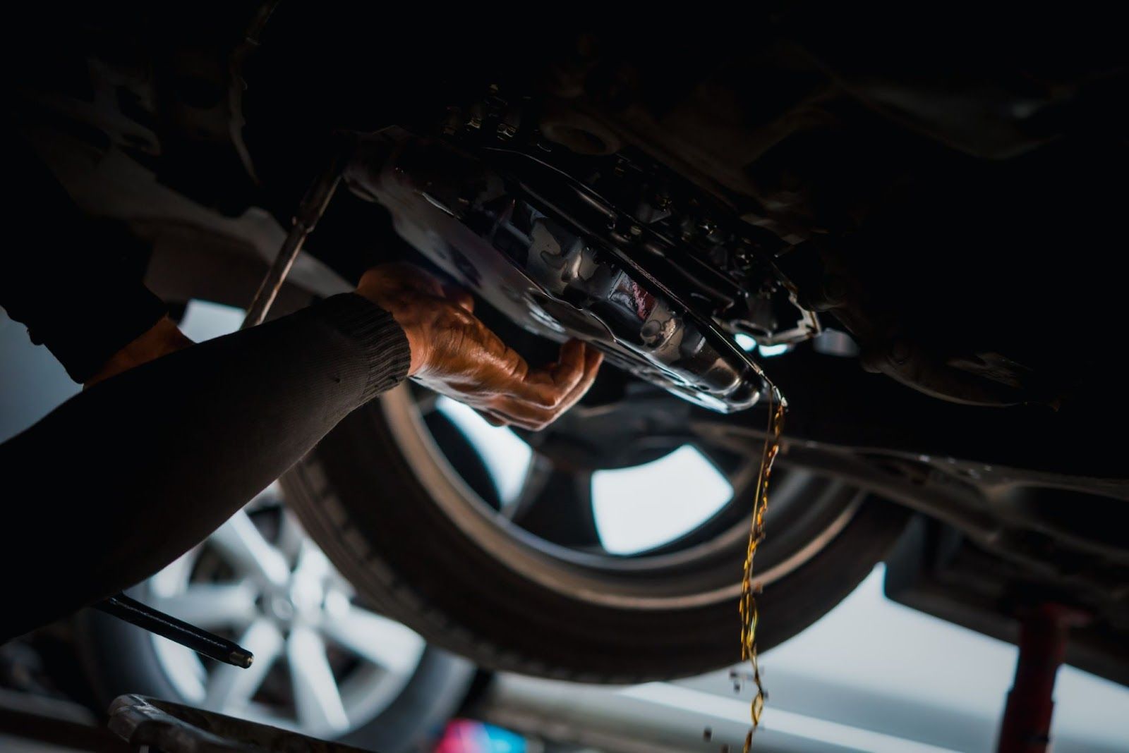 A person is working on the underside of a car.