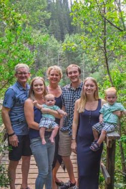 A family is posing for a picture on a bridge in the woods.