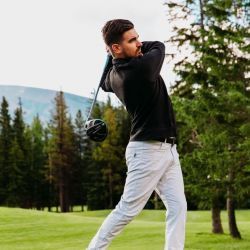 A man is swinging a golf club on a golf course.