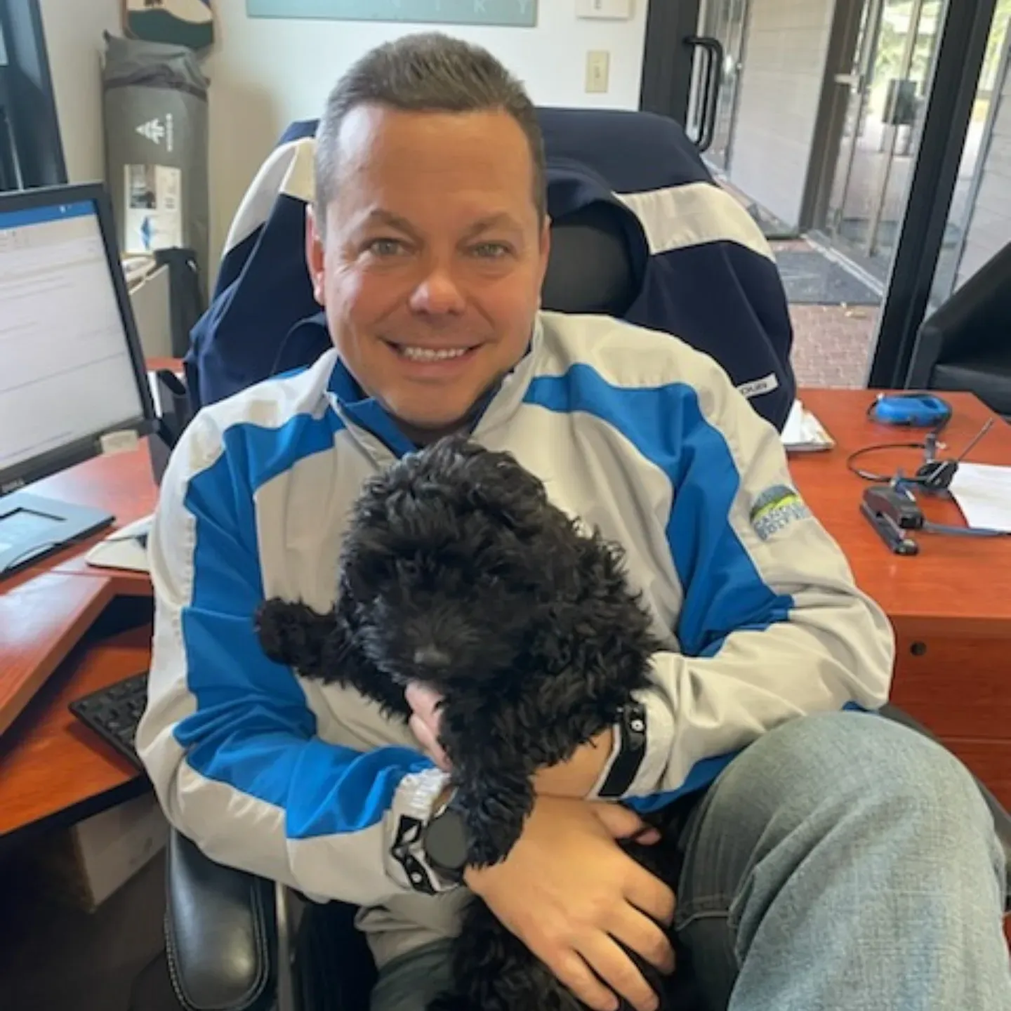 A man in a green jacket is smiling for the camera.