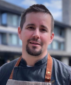 A man with a beard is wearing an apron