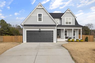 Gray two-story house with a front porch, double garage, and concrete driveway
