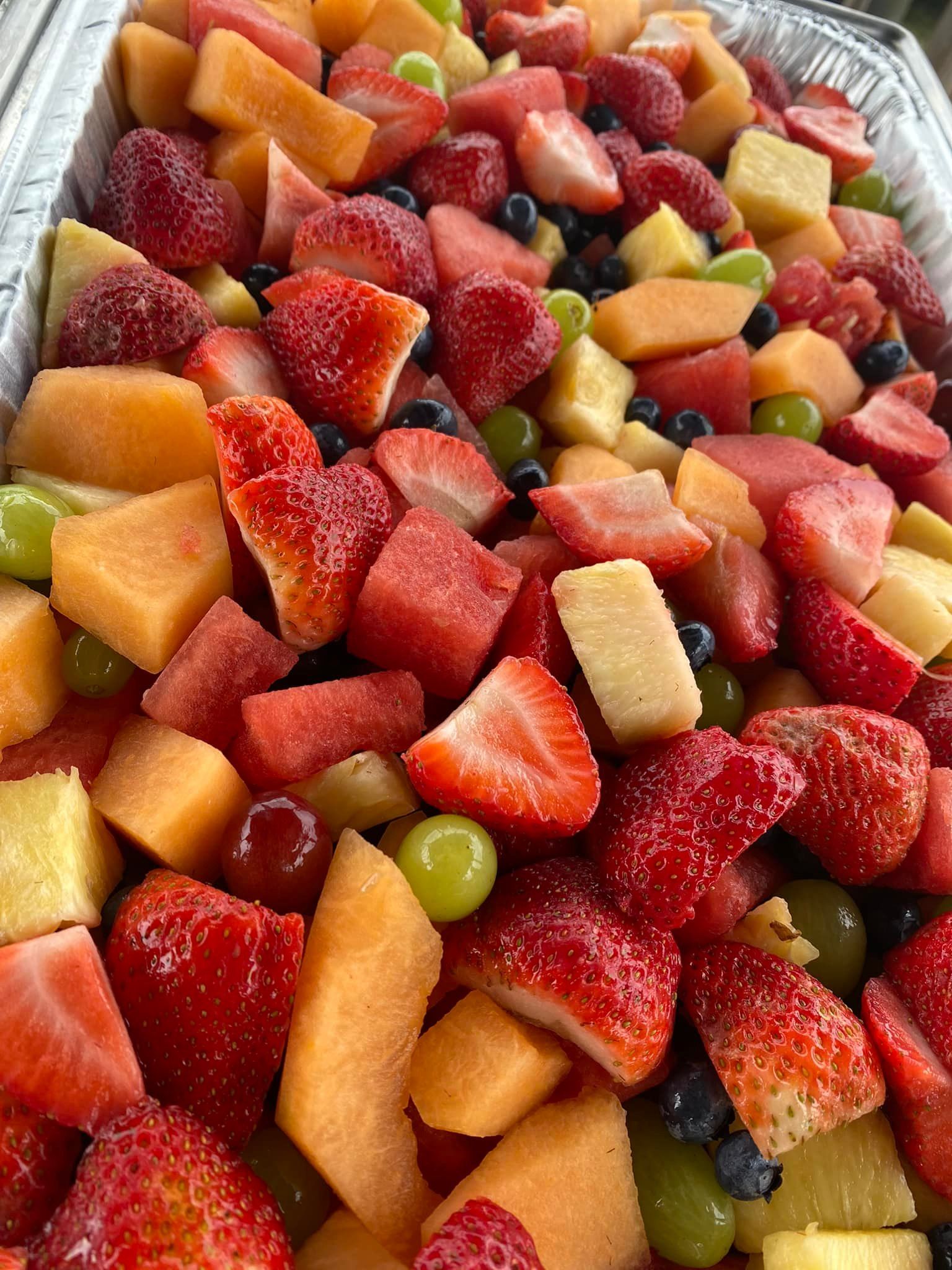 A close up of a fruit salad with strawberries , watermelon , grapes and melon.