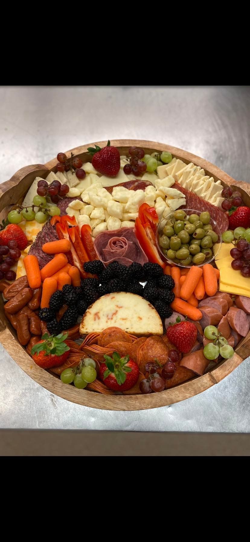 A wooden bowl filled with a variety of fruits and vegetables.