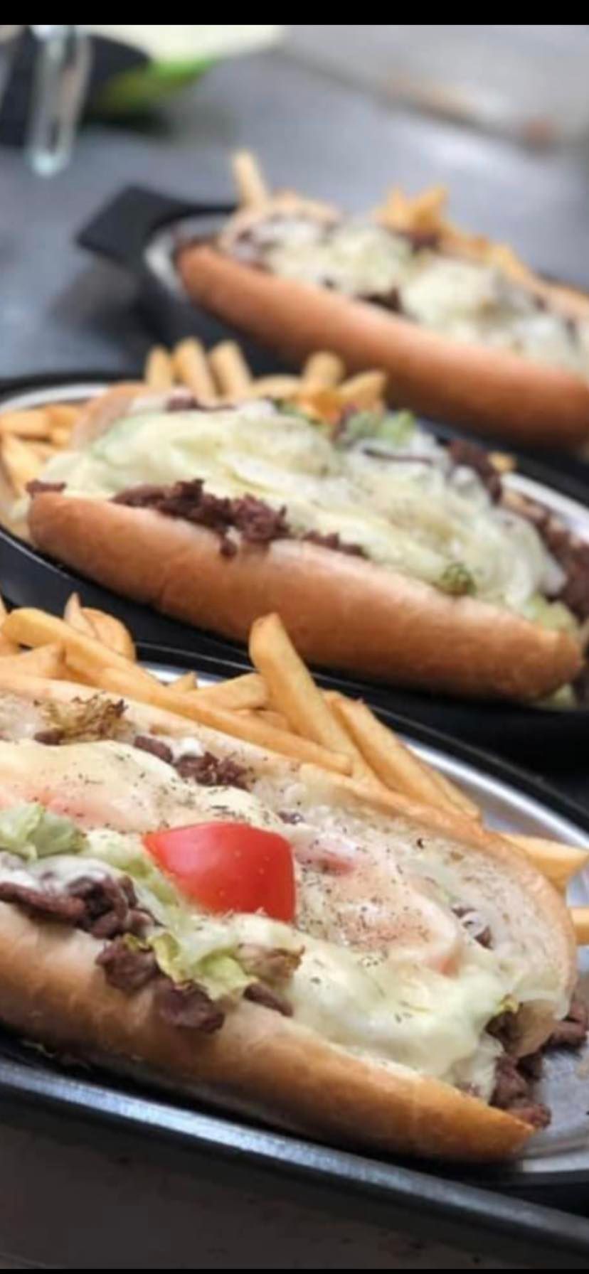 Three sub sandwiches with french fries on a plate on a table.