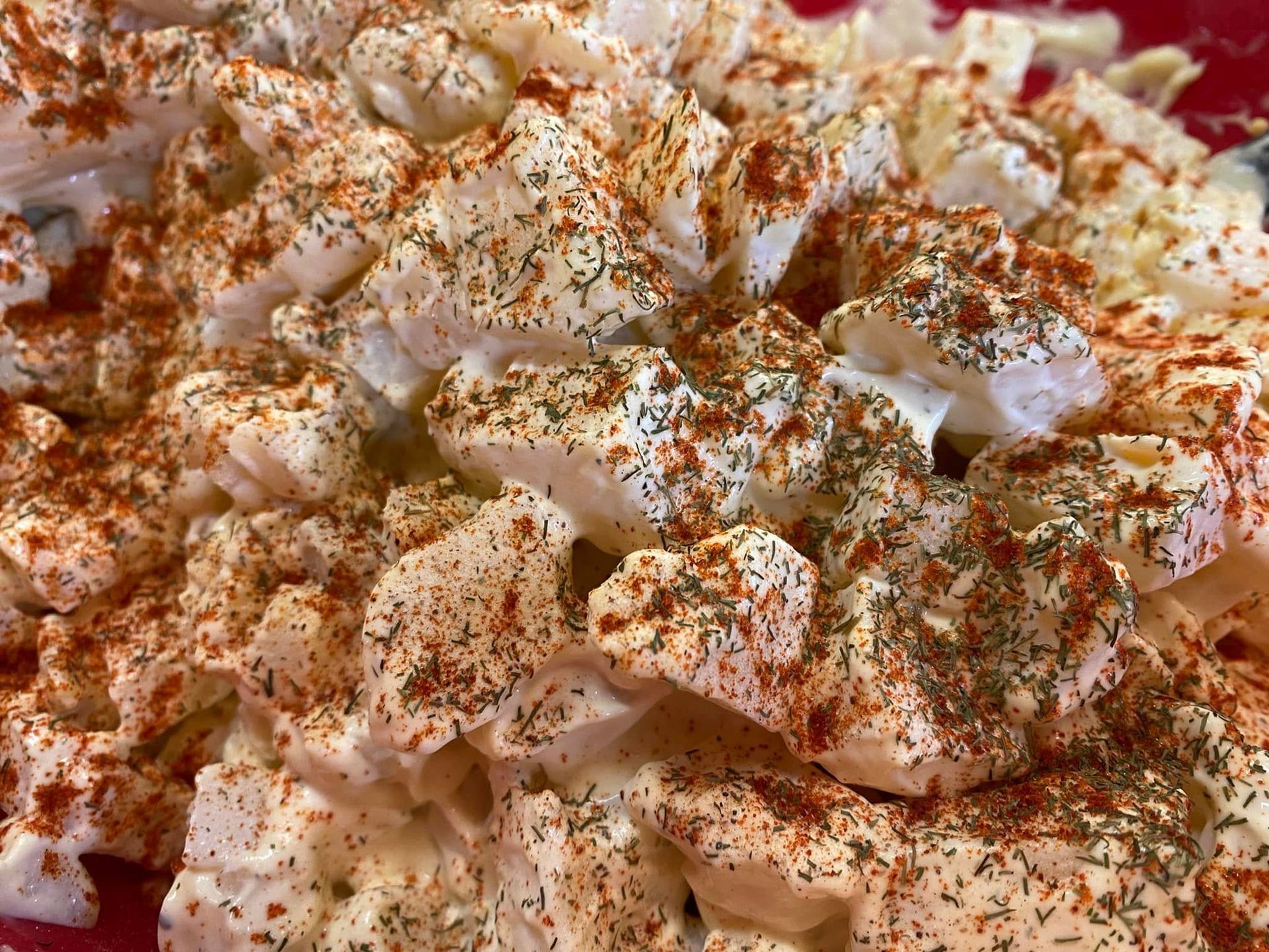 A close up of a potato salad on a red plate.