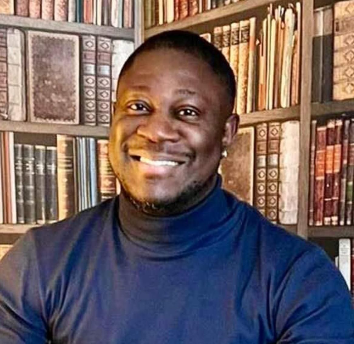 Eine  Person in einem dunkelblauen Rollkragenpullover posierte vor einem Bücherregal voller antiker, ledergebundener Bücher.