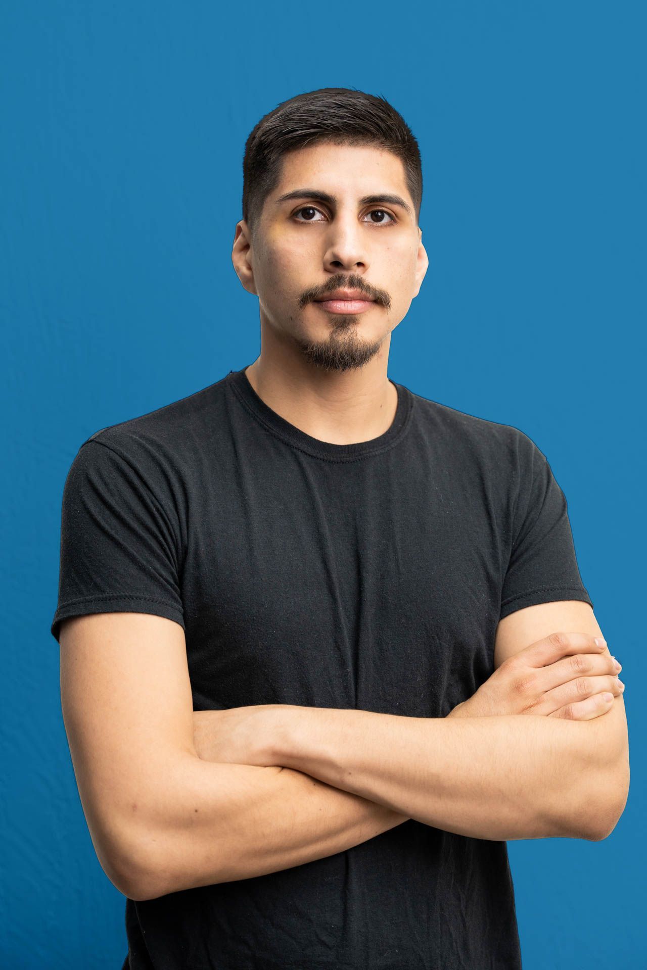 A man in a black t-shirt is standing with his arms crossed.