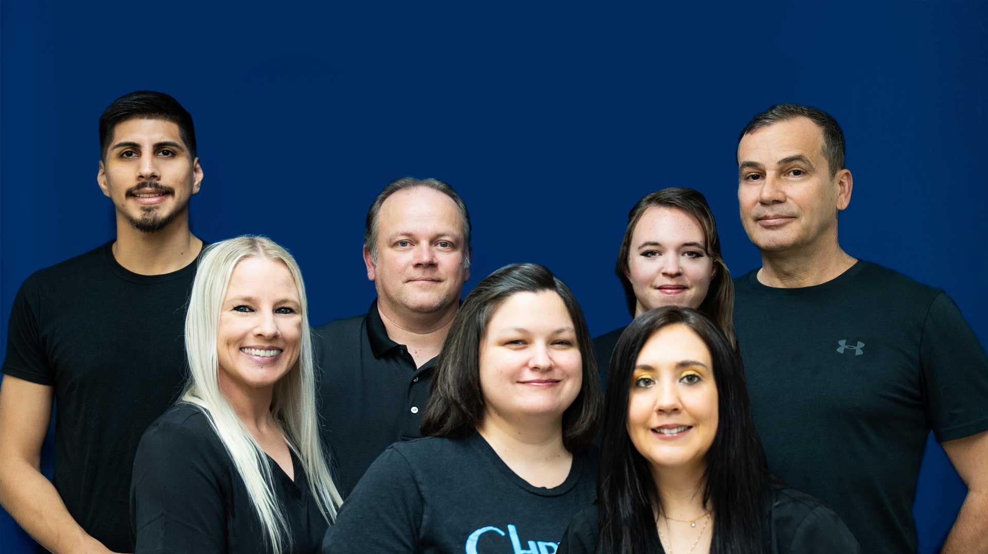 A group of people are posing for a picture in front of a blue wall.