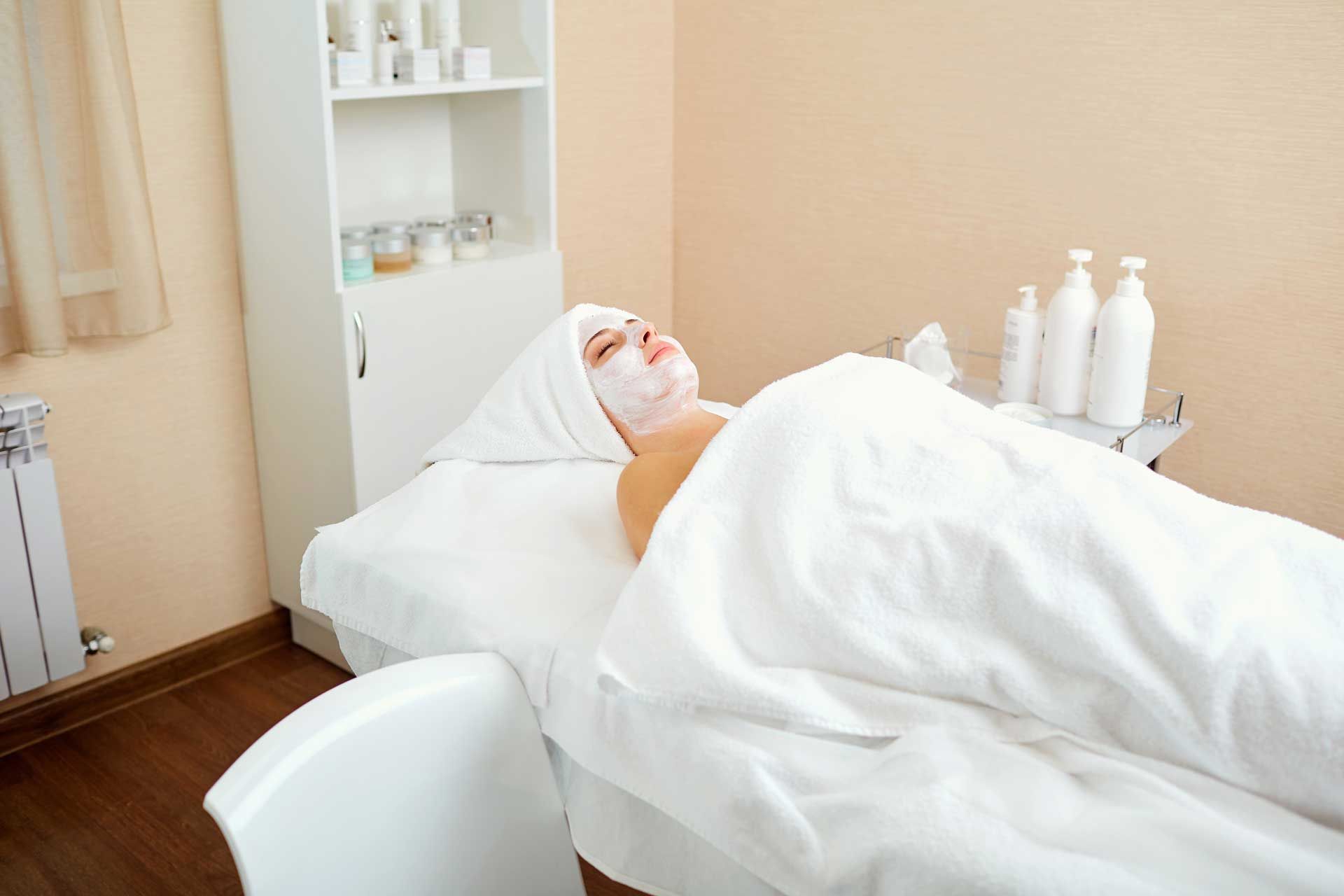 A woman is laying on a bed with a mask on her face.