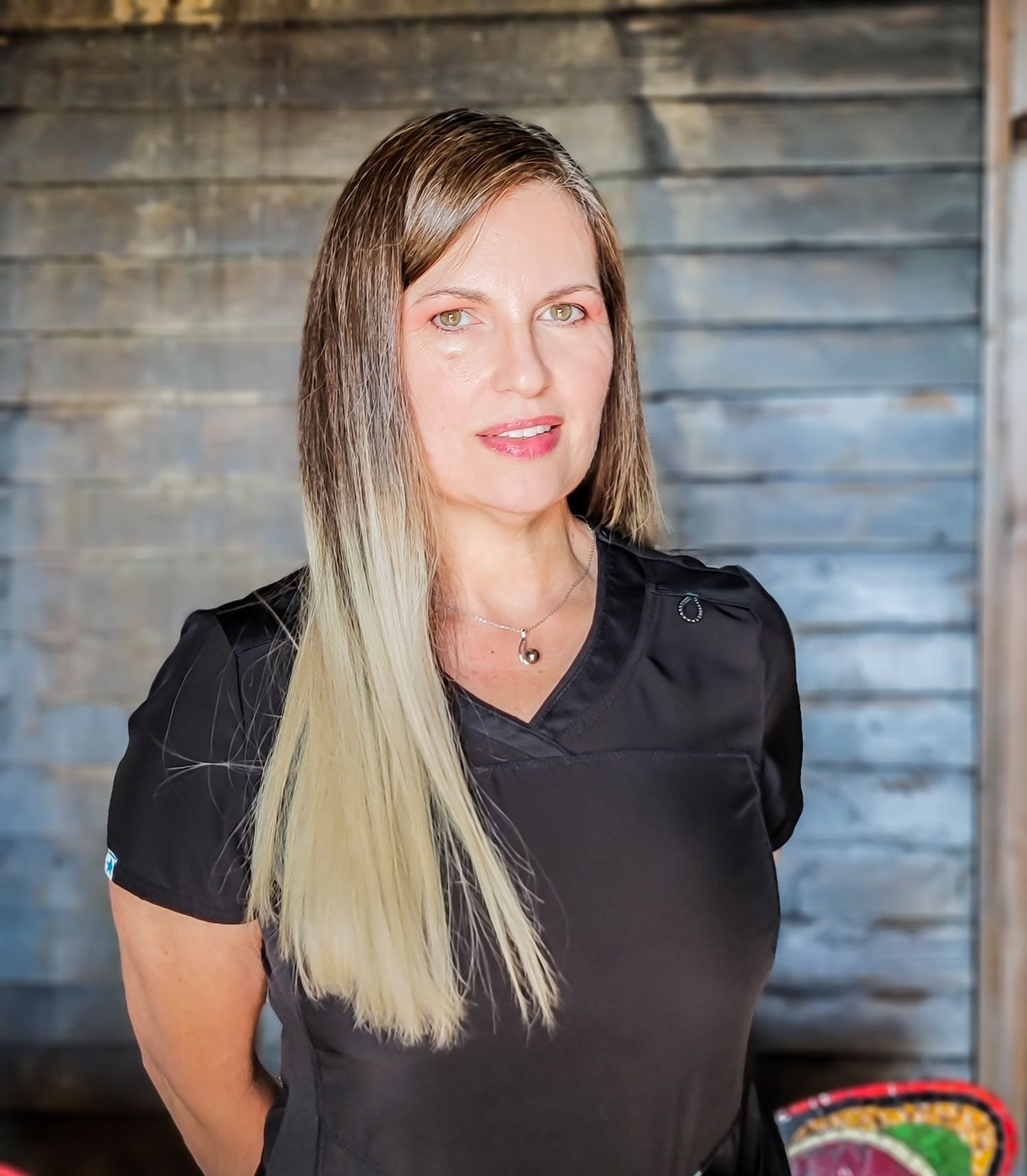 A woman in a black shirt is standing in front of a wooden wall.