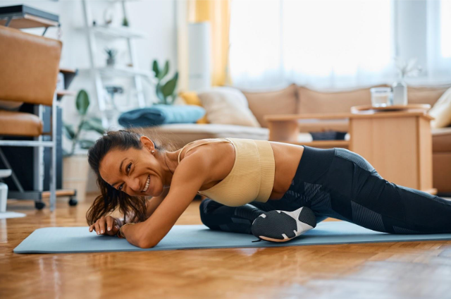 a woman is doing a plank on a yoga mat in a living room .