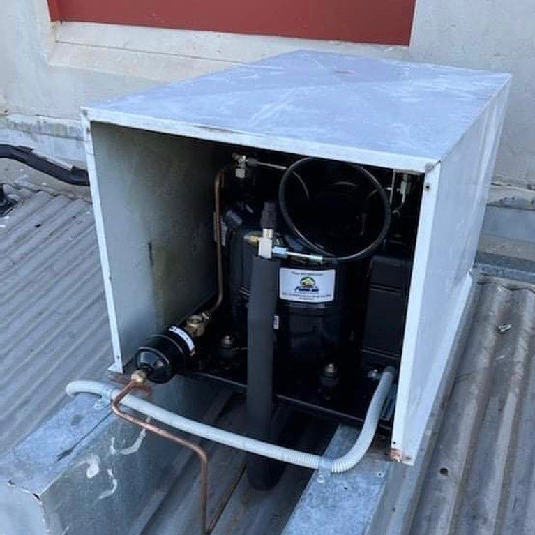 A Compressor Is Sitting Inside Of A White Box On A Roof — Frigid-Air PTY Ltd In Evans Head, NSW