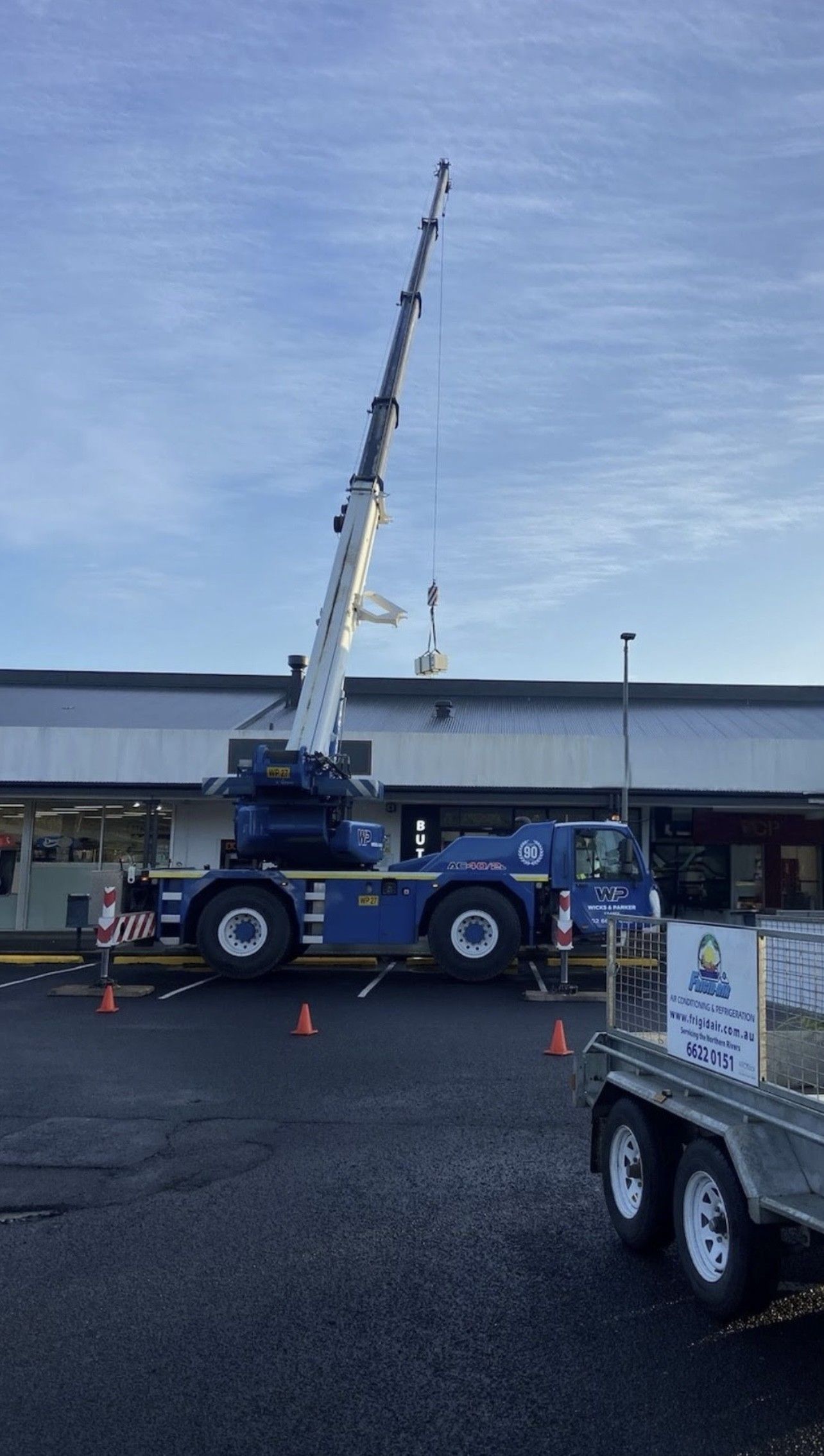 A Crane Is Lifting A Large Gray Box From The Roof Of A Building — Frigid-Air PTY Ltd In South Lismore, NSW