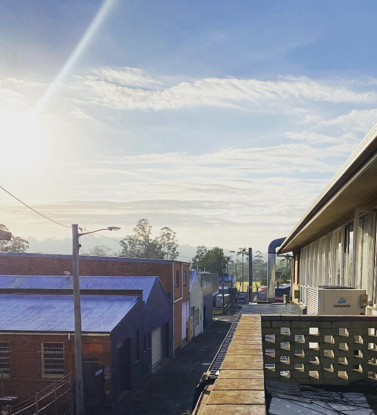 A Balcony Overlooking A Row Of Buildings With The Sun Shining Through The Clouds — Frigid-Air PTY Ltd In Evans Head, NSW