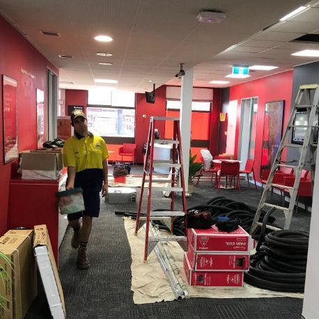 A Man Is Walking Through A Room Filled With Boxes And A Ladder — Frigid-Air PTY Ltd In South Lismore, NSW