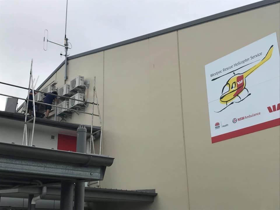 A Sign On The Side Of A Building Shows A Helicopter — Frigid-Air PTY Ltd In South Lismore, NSW