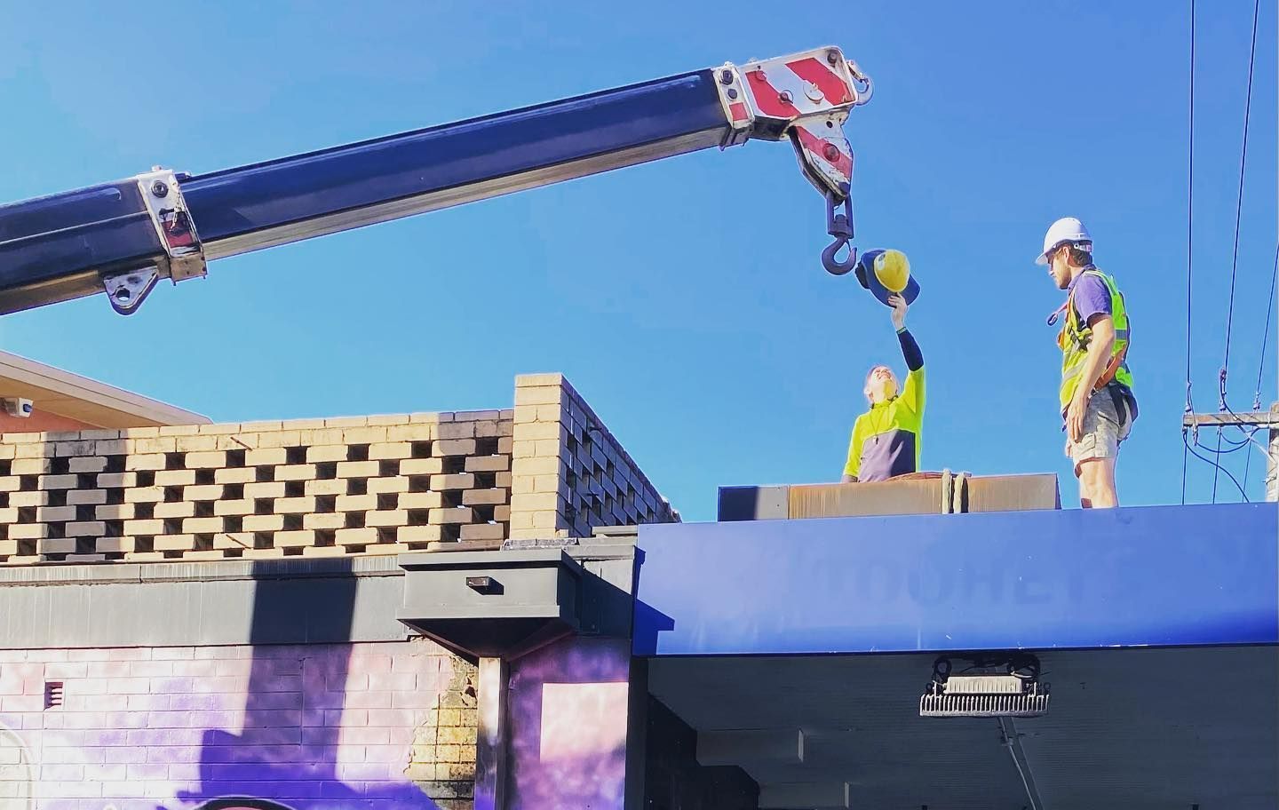 A Group Of Construction Workers Are Working On A Roof With A Crane — Frigid-Air PTY Ltd In Wollongbar, NSW