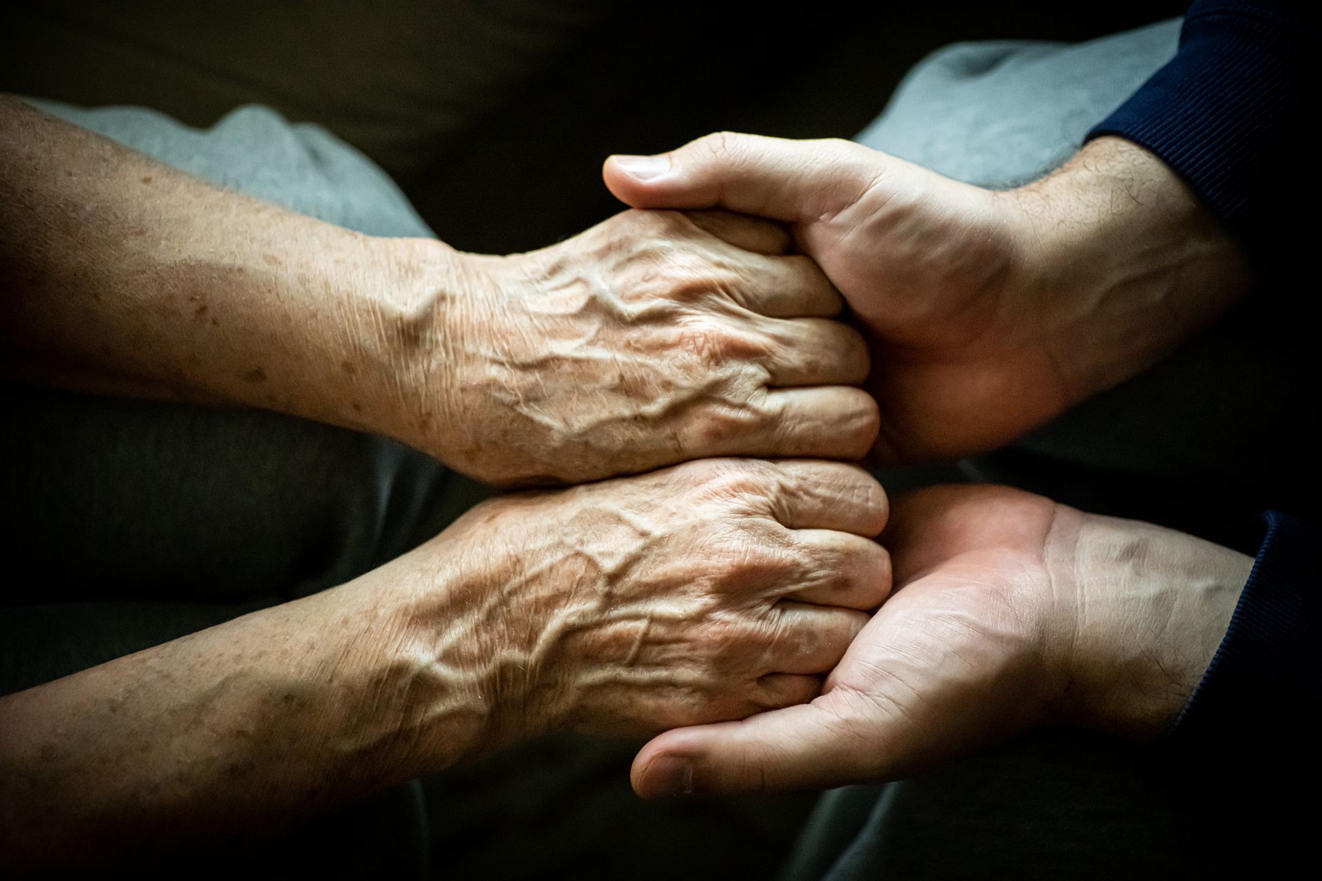 A man is holding the hands of an older woman.