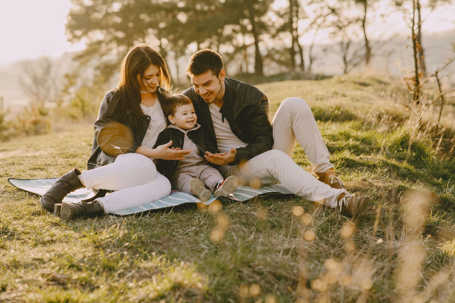 A family is sitting on a blanket in the grass.