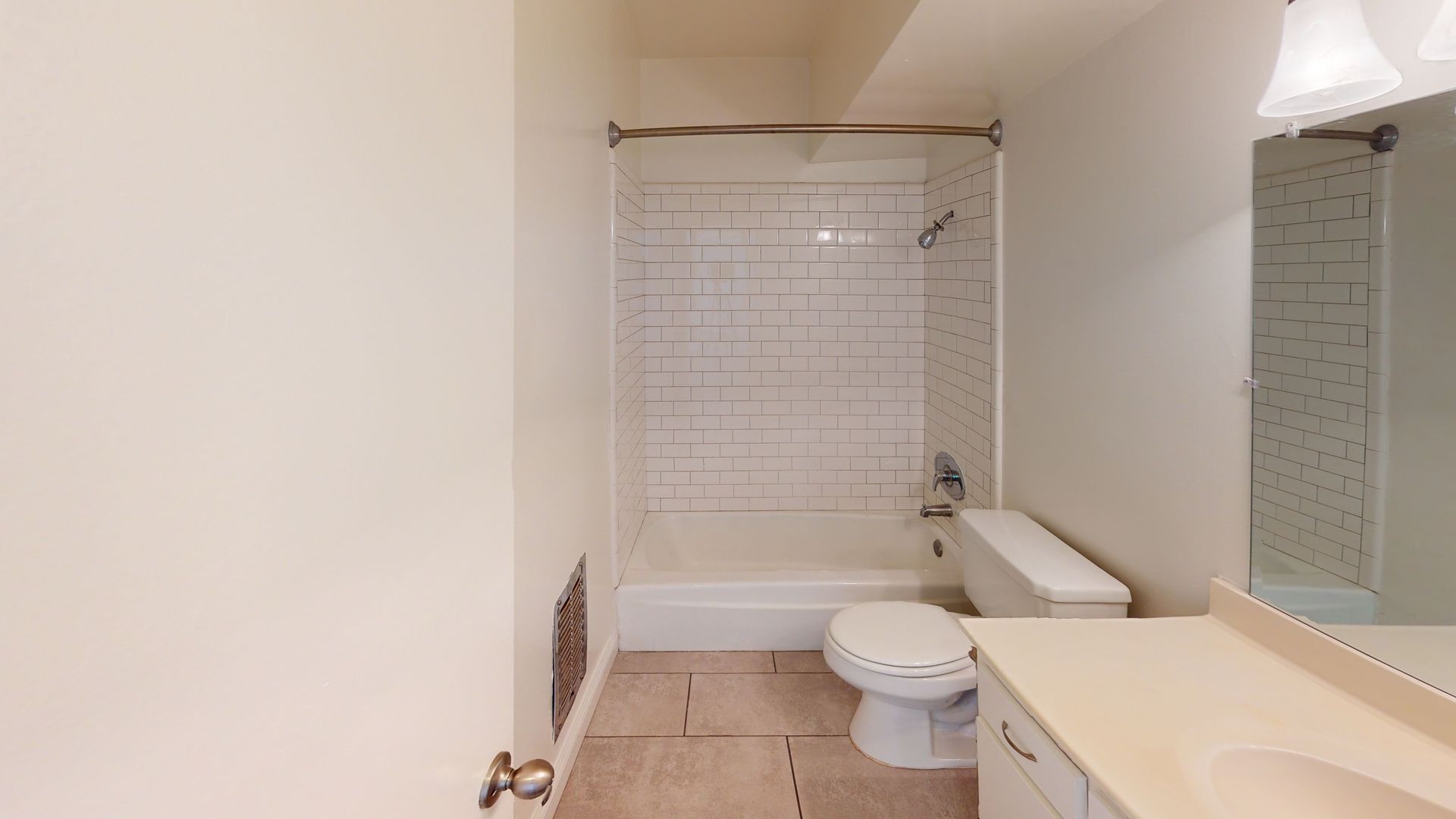 Bathroom with white walls, a bathtub, toilet, and sink.