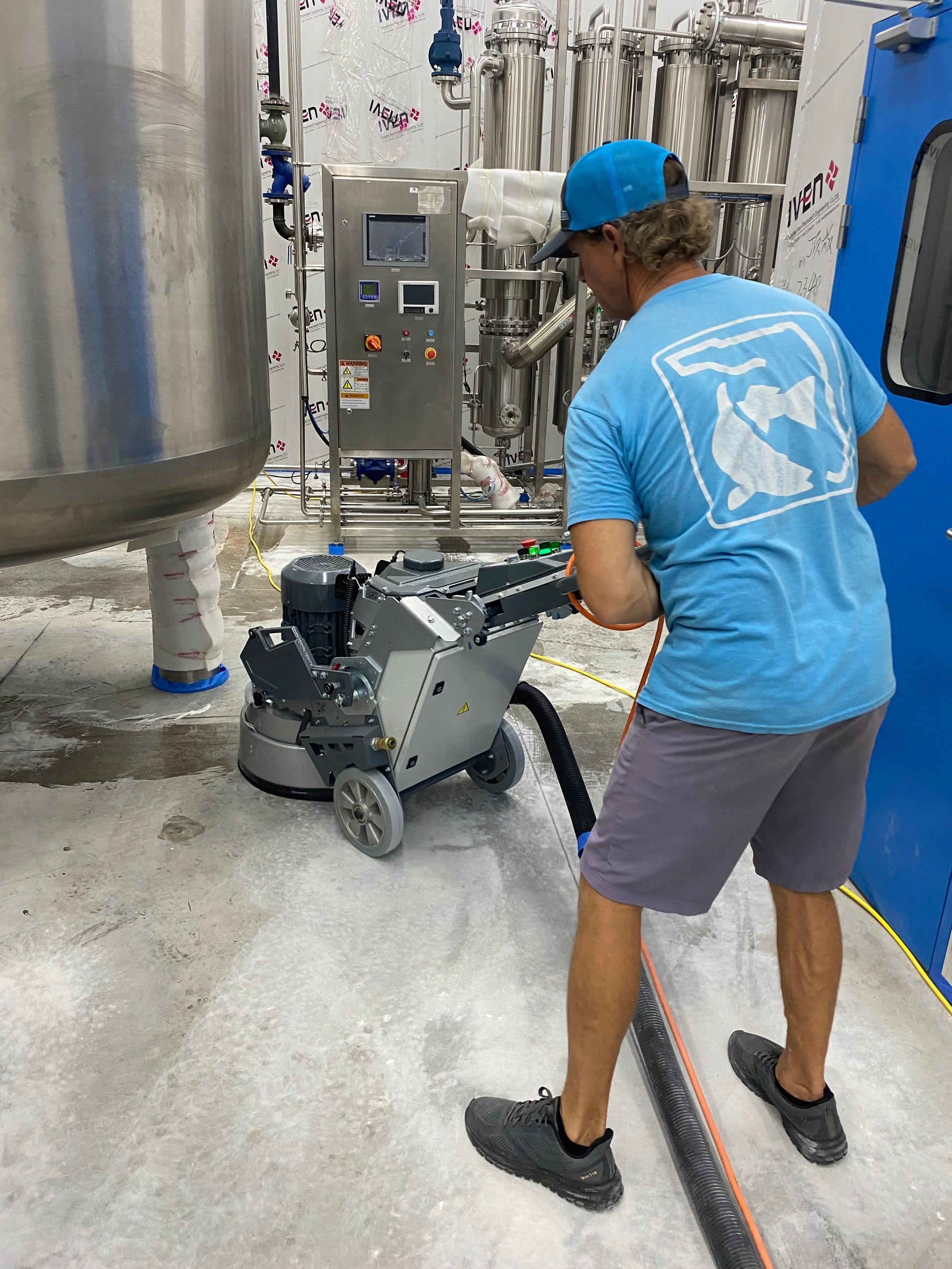Person operating floor grinder in industrial setting.