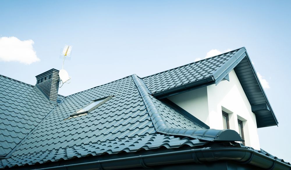 Dark Gray Metal Roof on a White House, Against a Blue Sky — Callaway Roofing & Construction in Cowra, NSW