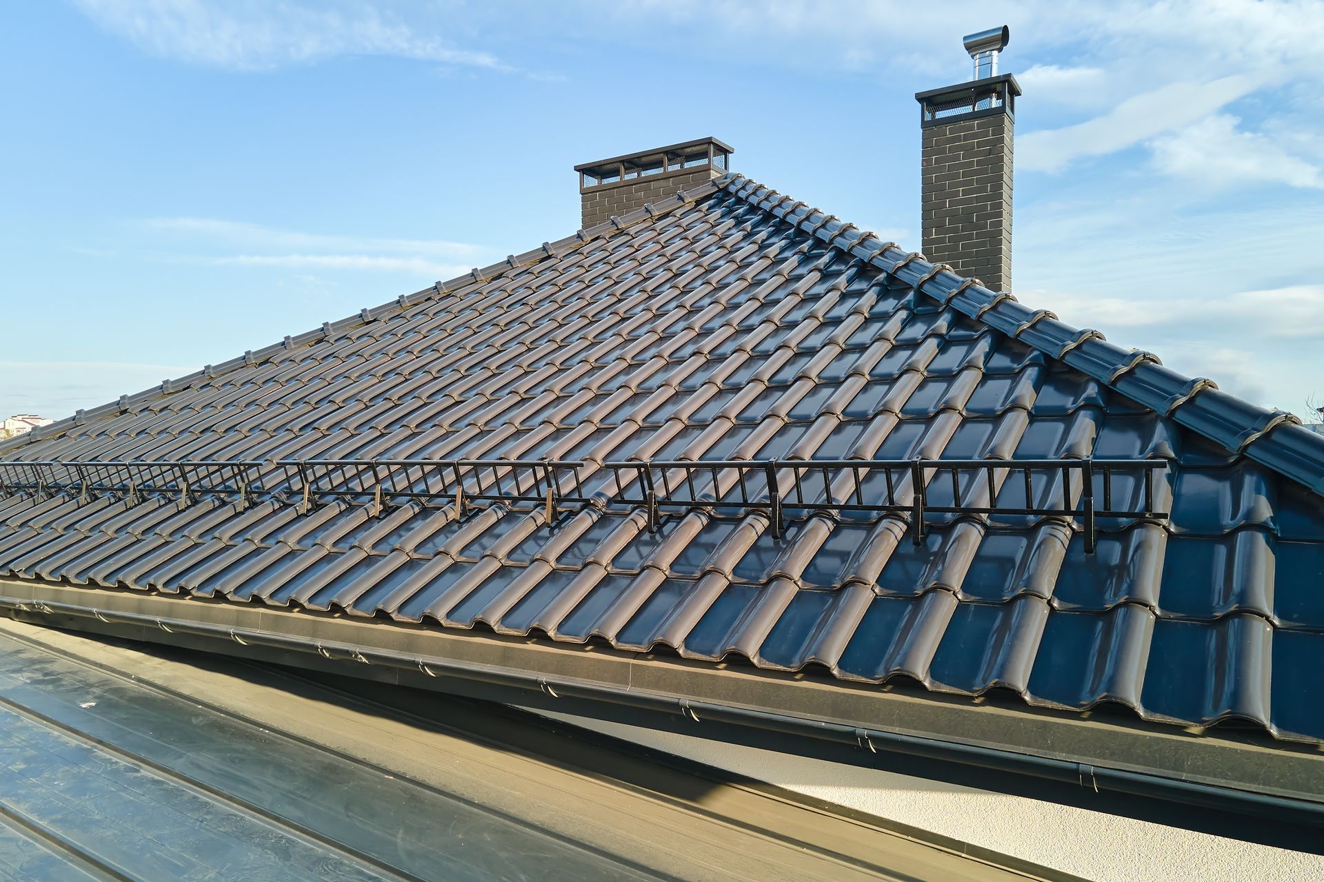 Dark Gray Tiled Roof With Black Metal Trim and Two Chimneys — Callaway Roofing & Construction in Wellington, NSW