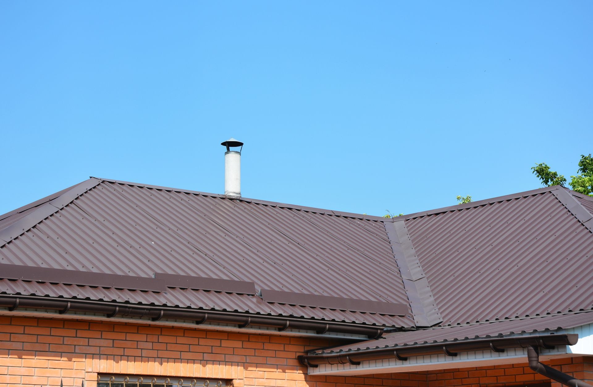 Brown Metal Roof on a Brick Building, With a Chimney Against a Blue Sky — Callaway Roofing & Construction in Orange, NSW
