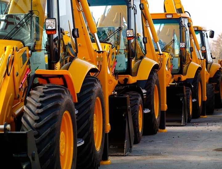 Una fila de tractores amarillos están estacionados en un estacionamiento.