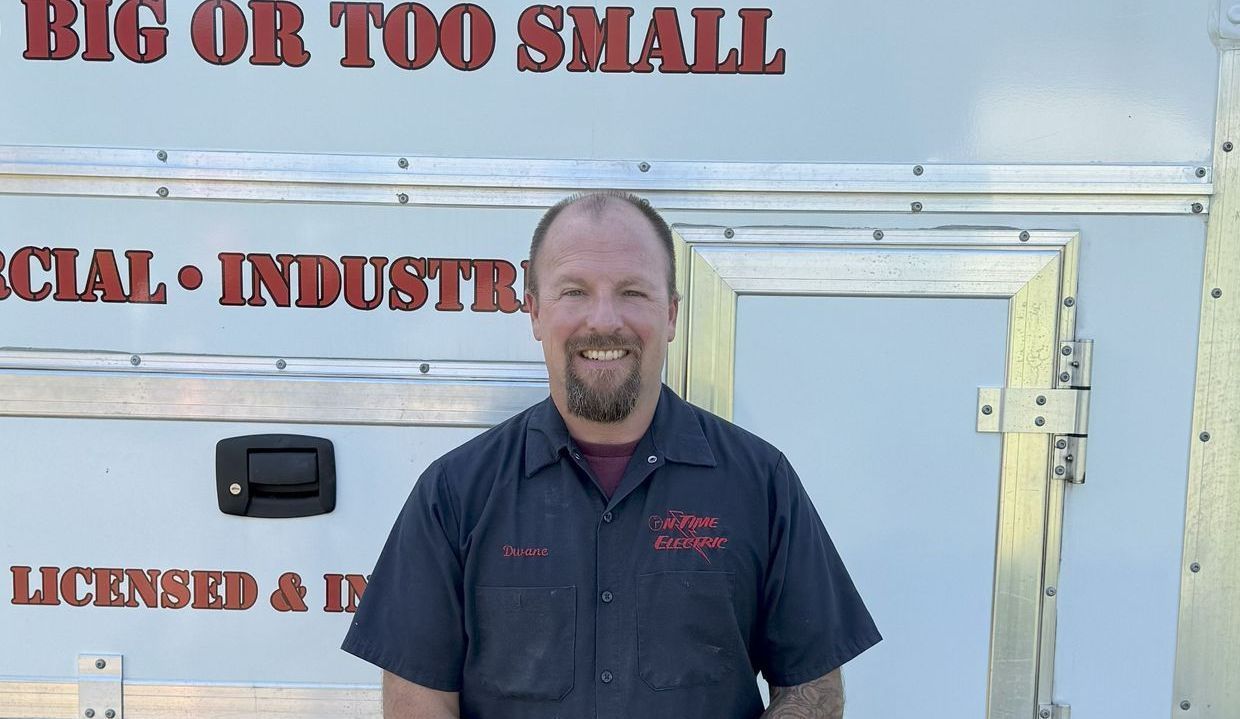 A man is standing in front of a trailer that says big or too small