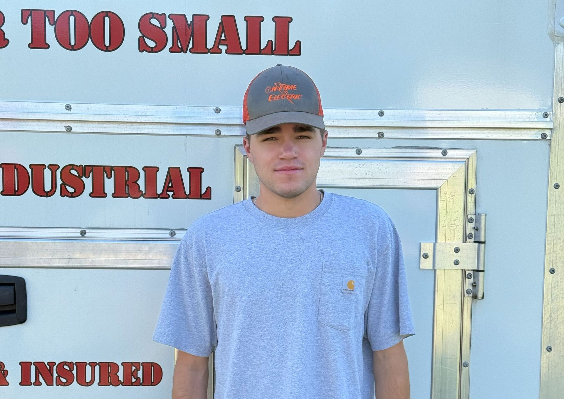 A man standing in front of a sign that says too small industrial insured